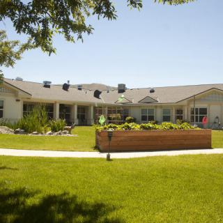 A sunny view of a building with a well-maintained lawn and garden.
