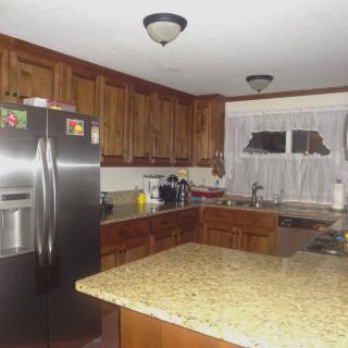 A modern kitchen with wooden cabinets, granite countertops, and stainless steel appliances.