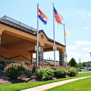 Hotel entrance with flags and well-maintained landscaping.