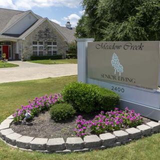 Entrance sign with flowers outside a school building.