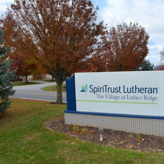 Entrance sign for SpiritTrust Lutheran, surrounded by autumn foliage.