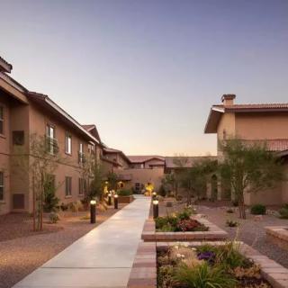 A quiet residential area with a central pathway, surrounded by desert-style landscaping and buildings.