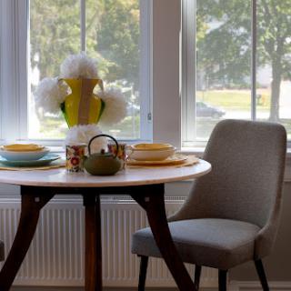 A cozy dining area with a well-set table, featuring vibrant dishes and tasteful decor, illuminated by natural light.