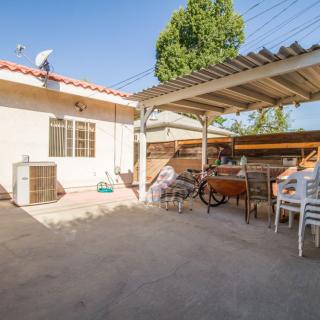 A sunny backyard patio with outdoor seating and a bicycle under a shade structure.