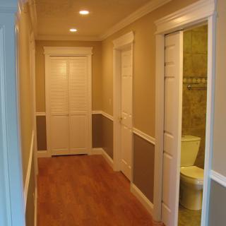 A well-lit hallway with wooden flooring and multiple doors.