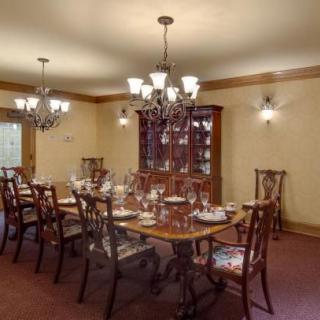 A traditional dining room with an elegant table setting and chandelier lighting.
