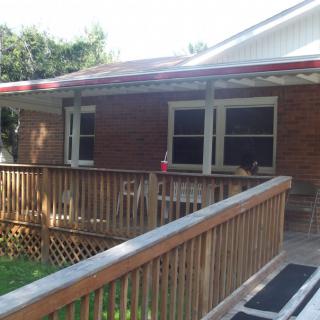 A brick house with a wooden porch and a ramp leading to the entrance.