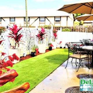 A well-designed patio with outdoor seating, adorned with potted plants and a neatly arranged artificial grass area.