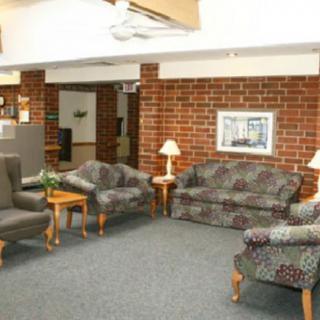 A cozy lobby area featuring sofas, chairs, and a table against a brick wall.