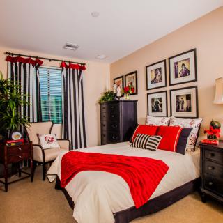 A stylish bedroom featuring a red and white color scheme, complete with modern furnishings and decorative wall art.