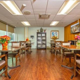 A well-lit dining area with wooden floors and neatly arranged tables and chairs.