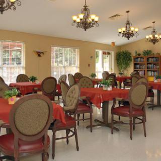A cozy dining room setup with red tablecloths, elegant chairs, and chandeliers.