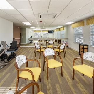 A well-lit exercise room equipped with chairs and fitness machines.