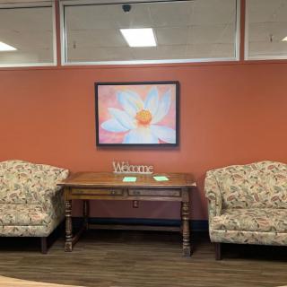 A cozy waiting area with floral upholstery chairs and a vibrant flower painting on the wall.