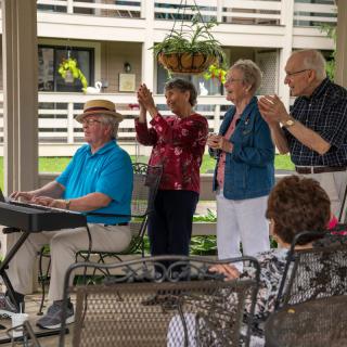 A keyboard player performs outdoors while an appreciative audience claps along.