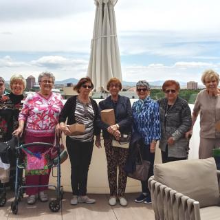 A group of women standing together on a patio with a scenic backdrop.