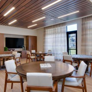 A modern meeting room with round tables, chairs, and a wooden ceiling design.