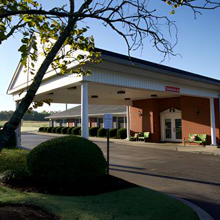 A building with an overhang structure and a surrounding landscaped area.