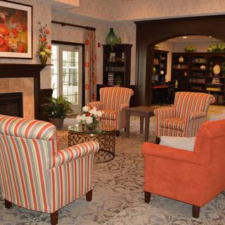 A cozy living room with striped and orange armchairs, a fireplace, and bookshelves.