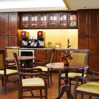 A cozy cafe interior with wooden tables and chairs, featuring a coffee station with machines.