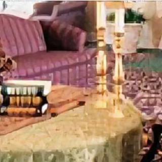 A cozy living room with a comfortable sofa, elegant candlesticks on the table, and a stack of books for reading pleasure.