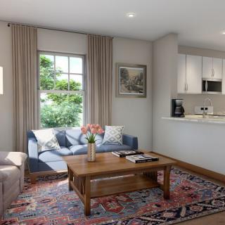 A cozy living room with a sofa, coffee table, and a view into the kitchenette.
