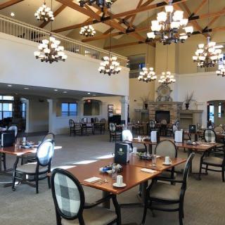 A spacious dining area with elegant chandeliers and neatly arranged tables and chairs.