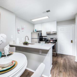 A modern kitchen with stainless steel appliances and white cabinetry, complemented by an adjacent dining area.