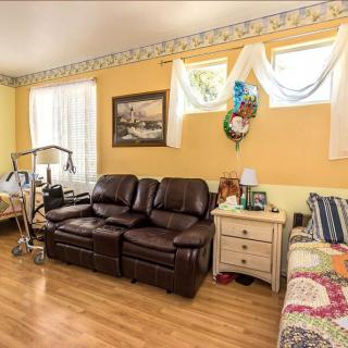 A cozy living room with a leather sofa, bed, and decorative elements like paintings and a wall clock.