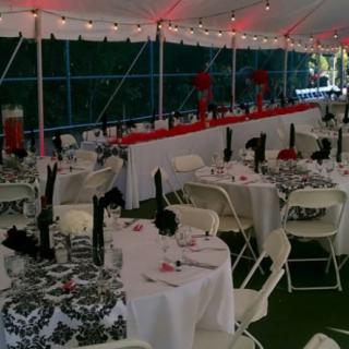An elegantly decorated outdoor wedding reception under a tent, featuring tables with patterned tablecloths and neatly arranged chairs.