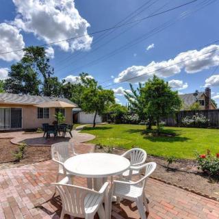A sunny backyard with a patio set, green lawn, and surrounding trees.