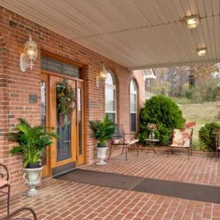 A welcoming porch entrance with brick walls, potted plants, and outdoor seating.