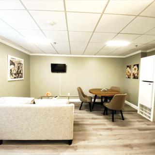 A modern living room featuring a cozy sofa, a round dining table with chairs, a mounted television, and artwork on the walls.