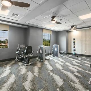 A modern fitness room with exercise equipment and weights.
