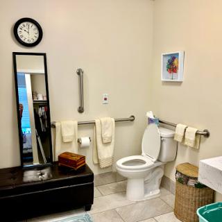 A well-organized bathroom featuring a toilet, mirror, and neatly arranged towels.