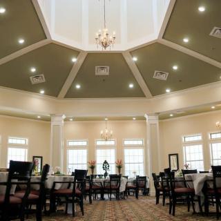 A spacious dining room with elegant interior design featuring a chandelier and neatly arranged tables and chairs.