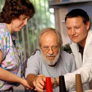 A therapist assists an elderly patient with a physical therapy exercise.