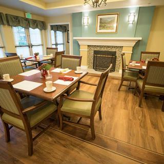 A cozy dining area with tables and chairs set near a fireplace.