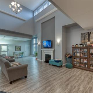 Spacious modern living room with high ceilings, featuring a fireplace and a television, complemented by elegant furniture and hardwood floors.