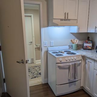 A modern kitchen featuring a stove and an open doorway leading to another room.