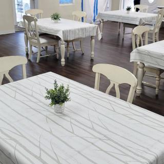 A quaint indoor restaurant setting with tables covered in white tablecloths and small plant decorations.