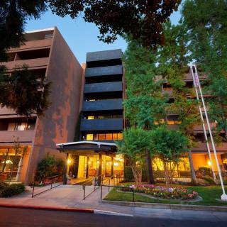 A welcoming hotel entrance illuminated at dusk with surrounding trees.