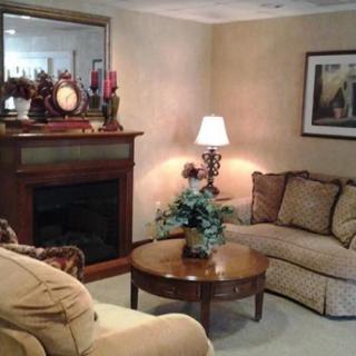 A cozy living room featuring a comfortable sofa, a coffee table with a decorative centerpiece, and a fireplace with a mirror above it.