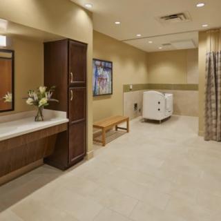 Modern bathroom interior with neutral tones, featuring a sink, mirror, and a bench.