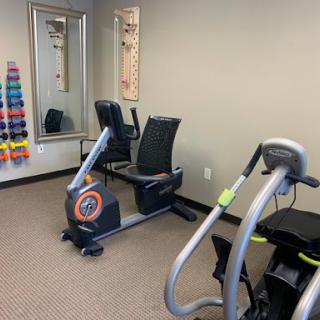 A small fitness area equipped with a recumbent bike, an elliptical machine, and a set of weights.