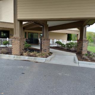 A view of the entrance to a building featuring a covered walkway and landscaped areas.