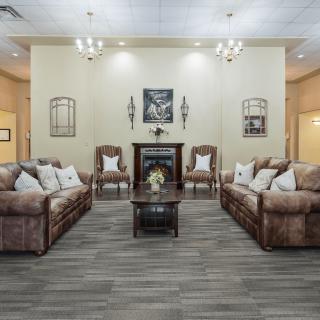 A spacious and well-decorated living room featuring comfortable sofas and armchairs arranged around a central fireplace.