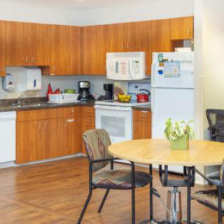 A cozy kitchen and dining area featuring wooden cabinets, a table with chairs, and various appliances like a refrigerator, microwave, and dishwasher.