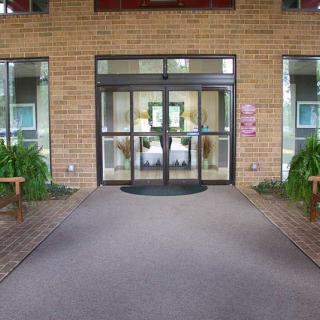 Entrance with glass doors and surrounding plants at a brick building.