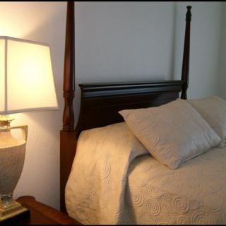 A cozy bedroom with a bed and a lit lamp.